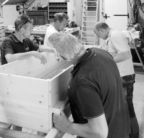 4 mannen aan het werk met de bouw van een houten grafkist